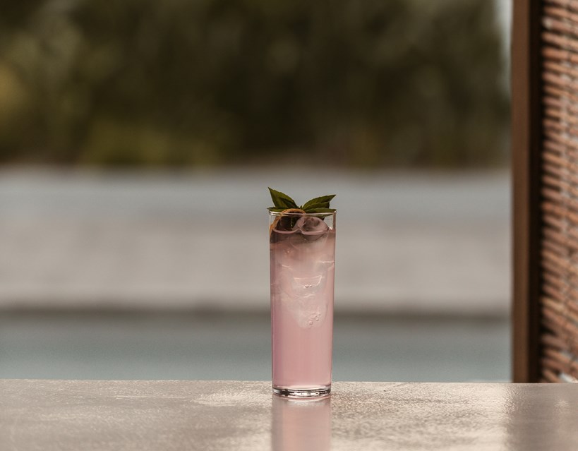 Casa Cook Rhodes fizzy pink drink with mint garnish sitting on a ledge by the pool